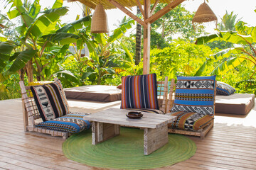 Lounge chairs with pillows and wooden table on the terrace. Cozy patio in hotel resort. Empty tourist villa. Outdoor design of luxury hotel. Leisure and relax concept. Summer vacations. 