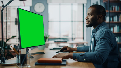 Aufkleber - Handsome Black African American Specialist Working on Desktop Computer with Green Screen Mock Up Display at Home Living Room. Freelance Man Chatting to Clients Over the Internet on Social Networks.