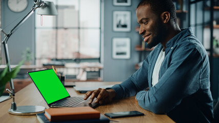 Aufkleber - Handsome Black African American Specialist Working on Laptop Computer with Green Screen Mock Up Display at Home Living Room. Freelance Man Chatting to Clients Over the Internet on Social Networks.