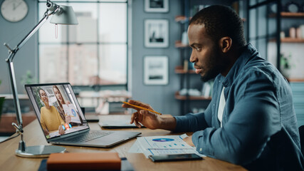 Aufkleber - Handsome African American Man Having a Video Call on Laptop Computer while Sitting Behind Desk in Living Room. Freelancer Working From Home and Talking to Colleagues and Clients Over the Internet.