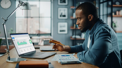 Aufkleber - Handsome Black African American Specialist Working on Laptop Computer in Creative Home Living Room. Freelance Male is Doing Market Analysis and Creates Report with Charts for Clients and Employer.
