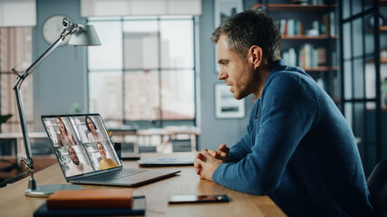 Aufkleber - Handsome Caucasian Man Having a Video Call on Laptop Computer while Sitting Behind Desk in Living Room. Freelancer Working From Home and Talking to Colleagues and Clients Over the Internet.