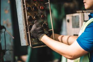 Work at factory.Close up hand of Asian worker man  working in safety work wear with yellow helmet and ear muff using equipment.in factory workshop industry machine professional