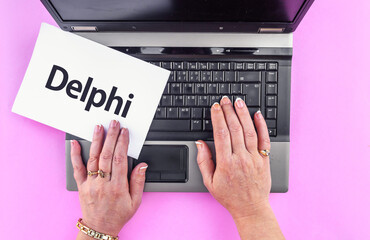 Poster - Delphi programming language. Word Delphi on paper and laptop
