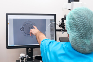 Embryologists perform test with human eggs. Doctor working on manipulator fertilizing human egg in fertility clinic lab, explaining the process, IVF treatment. Artificial insemination clinic.