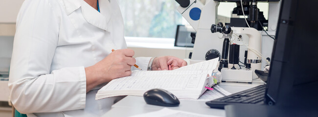 Doctor or scientist working with computer and microscope in biotech lab. Equipment in laboratory of Fertilization, IVF.