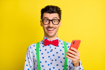 Poster - Photo of young excited man happy positive smile use cellphone chat type sms isolated over yellow color background