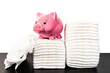 pink piggy bank on stack of disposable diapers against white background