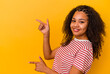 Young african american woman isolated on yellow background excited pointing with forefingers away.