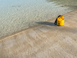 Closeup of vivid waterproof bag and shadow on the beach and sea background. Summer or travel concept and idea.
