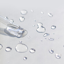 Liquid Gel Or Serum Pipette With Drops On Gray Background