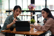 © amnaj - Two young Asian businesswoman brainstorm and analyze project using a tablet at the office.
