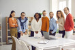 © Studio Romantic - Diverse dream team reaching success together. Group portrait of happy business people, colleagues and teammates looking at camera and smiling standing at office table after corporate work meeting