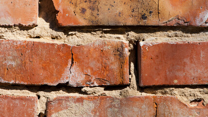Poster - broken old brick wall. Part of an old red brick wall with cement. Close-up old texture, worn wall of red stones. Falling brickwork with cement. a wall with cracks. close-up, for background and text