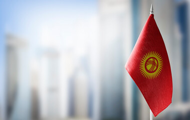 Sticker - A small flag of Kirghizia on the background of a blurred background