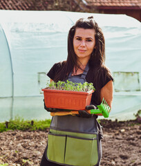  Pretty woman planting  vegetables in the garden.Young pretty Woman gardening in backyard on a sunny spring day .Agriculture and plant grow.Germinating seedling grow step sprout growing from seed. 