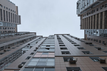 view from below of part of typical modern high-rise building against the gray cloudy sky. Geometry of the cities.