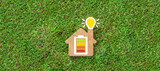 Fototapeta Zwierzęta - Energy efficiency and rating chart in a small model house with glowing lightbulb in the chimney over green grass in an ecological and environmental concept
