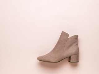 Light women's beige suede boot on a light beige background. Flat lay.