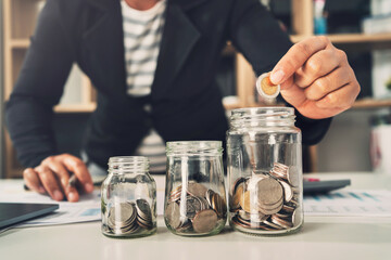 Poster - saving money with hand putting coins in jug glass concept financial