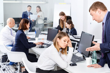 Wall Mural - Outraged angry unhappy manager expressing dissatisfaction with work of frustrated young pleasant woman in modern office