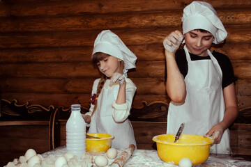 Brother and sister knead dough together. Family traditions. Baking process. Wooden background.