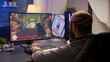 © DC Studio - Back view of pro man gamer sitting on gaming chair at desk and playing first person shooter video games at powerful computer. Digital gamer streaming online gameplay tournament with RGB neon lights