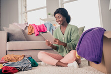 Portrait Of Attractive Cheerful Girl Sitting On Floor Using Ebook Selling Clothes Web Store In Flat House Living-room Indoor