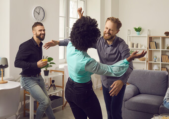 It's good to see you again. Two happy young people smiling and hugging each other as they meet at friend's party. Diverse group of millennial men and women enjoying reunion and having fun together