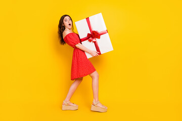 Sticker - Full size profile photo of impressed girl arms hold big heavy giftbox open mouth isolated on yellow color background