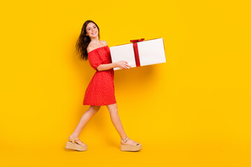 Poster - Full body profile photo of pretty positive lady arms hold big giftbox look camera isolated on yellow color background