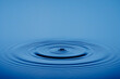 © Andreas Fischer - Closeup Water drop or splash falling on the surface of the water and beautiful circular wave ripple, water concept, with blue background