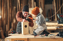 Kid With Dad Assembling Wooden Bird House In Craft Workshop