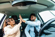 © F8  \ Suport Ukraine - Beautiful young indian couple is giving high five and smiling while travelling by car