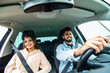 © F8  \ Suport Ukraine - Young indian man and woman smiling while seated in a new car.