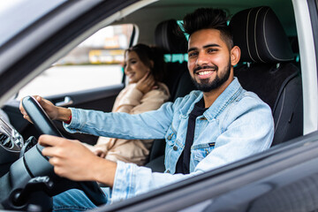 leisure, road trip, travel, family and people concept. Young happy indian man and woman driving in car