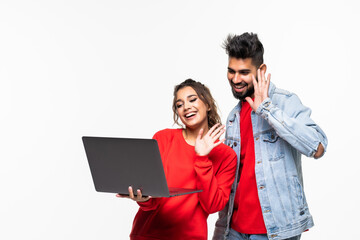 Wall Mural - Young indian couple with laptop make video call on white background