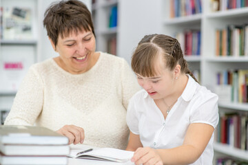 Poster - Teacher and girl with syndrome down read a book at library. Education for disabled children concept