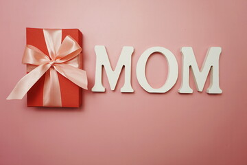 MOM word and gift box present on pink background