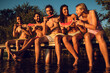 © Zoran Zeremski - Friends sitting on the edge of a pier enjoying on a summer day at the lake eating watermelon.