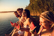 © Zoran Zeremski - Friends sitting on the edge of a pier enjoying on a summer day at the lake eating watermelon.