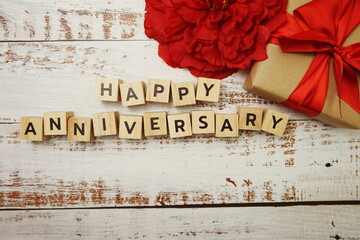 Happy Anniversary alphabet letter with gift box on wooden background