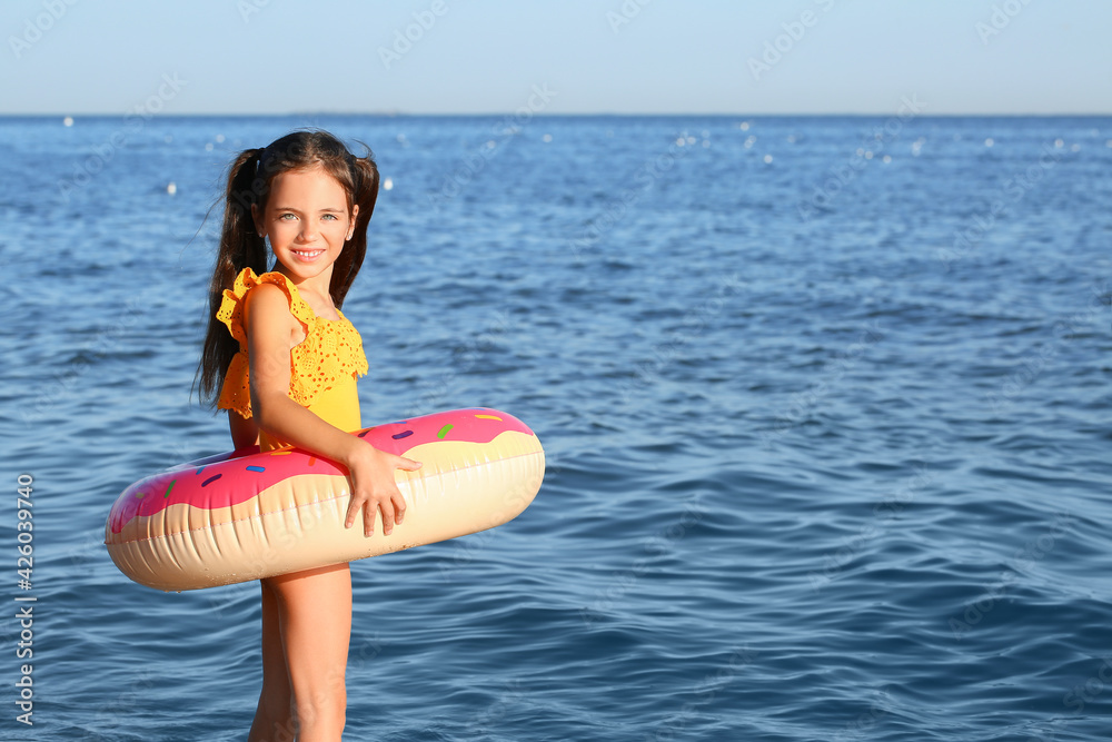 Cute little girl with inflatable ring on sea beach
