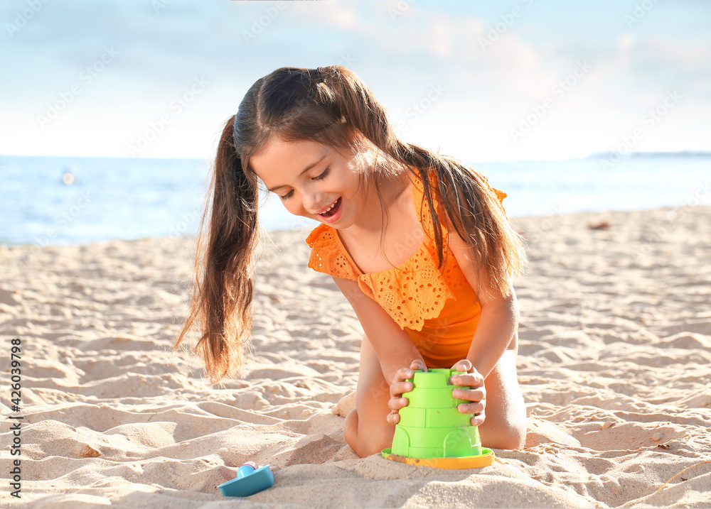 Cute little girl playing with sand on sea beach Stock Photo | Adobe Stock
