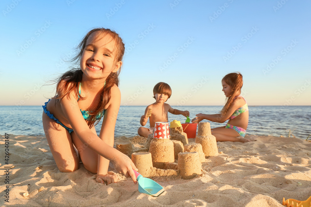 Cute little girl playing with sand on sea beach