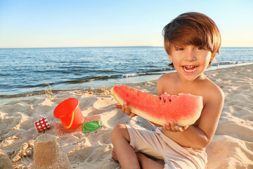 Wall Mural - Little boy eating watermelon on sea beach