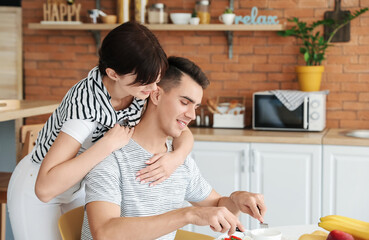 Poster - Young woman feeding her husband in kitchen