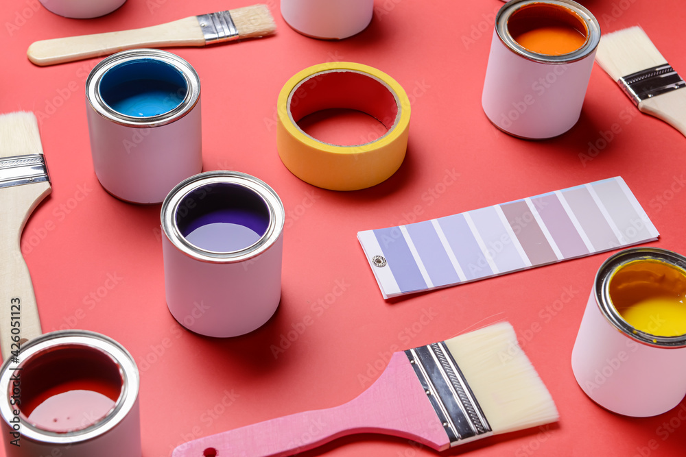 Cans of paints, palette sample and brushes on color background