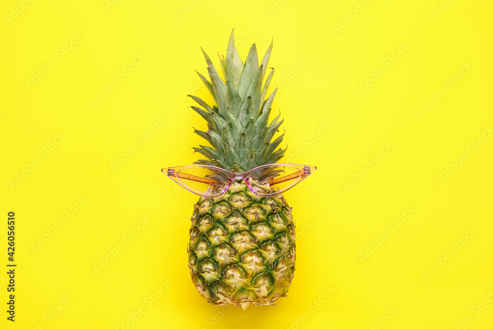 Pineapple with sunglasses on color background