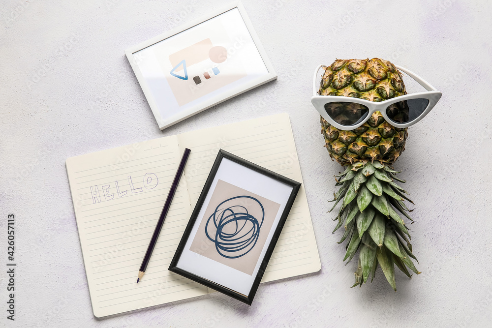 Pineapple with sunglasses, notebook and pictures on white background